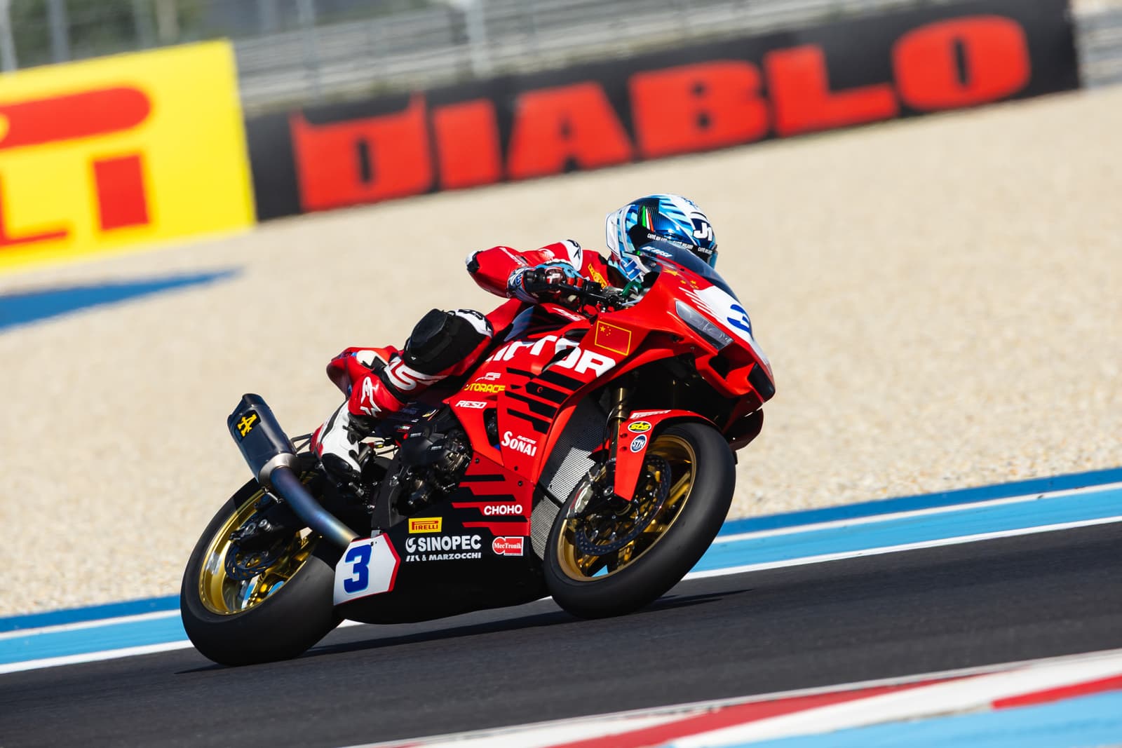 QJMOTOR racing motorcycle leaning into a corner on the track.